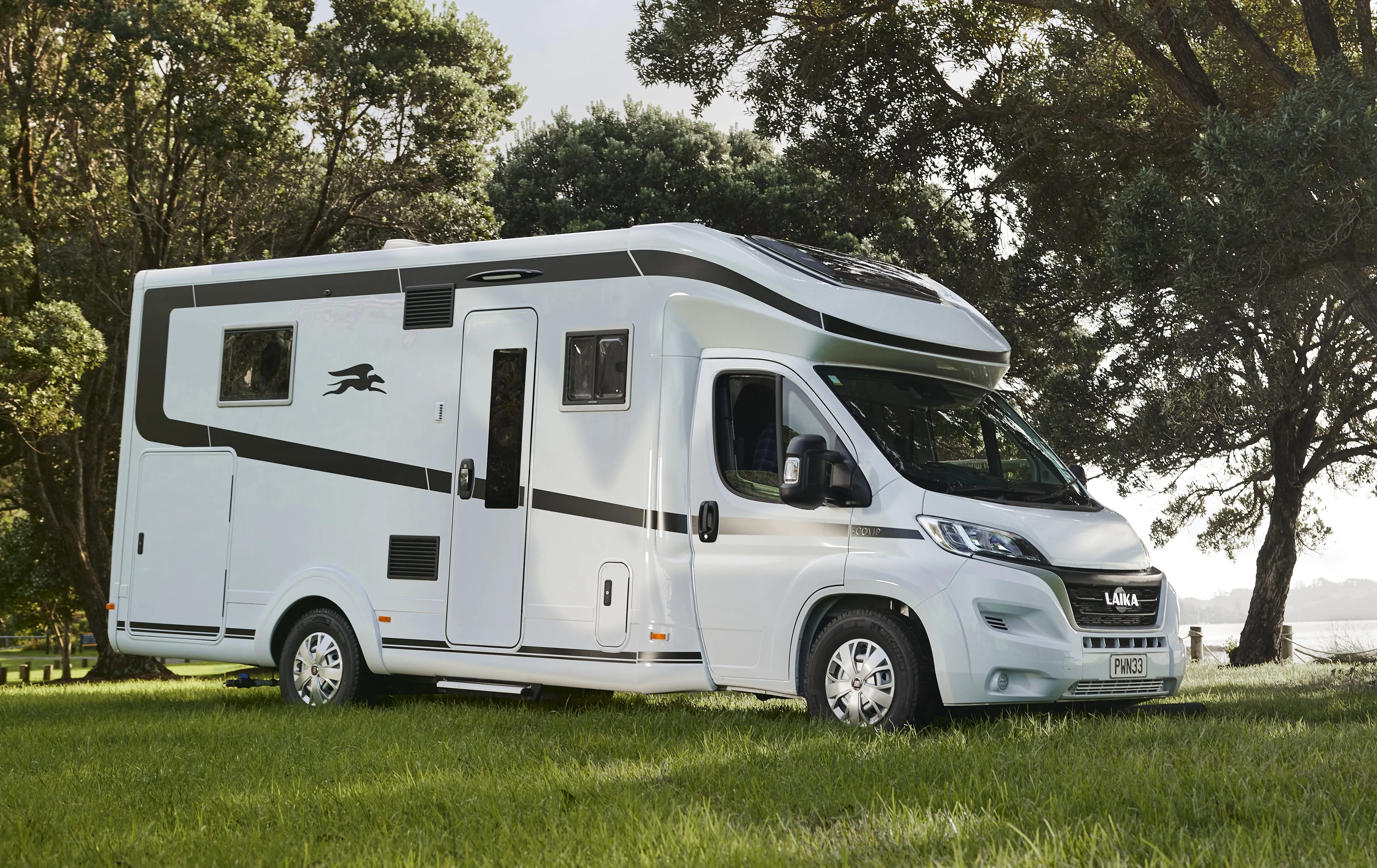 Teilintegrierte Wohnmobil weiß auf grünem Rasen vor Bäumen