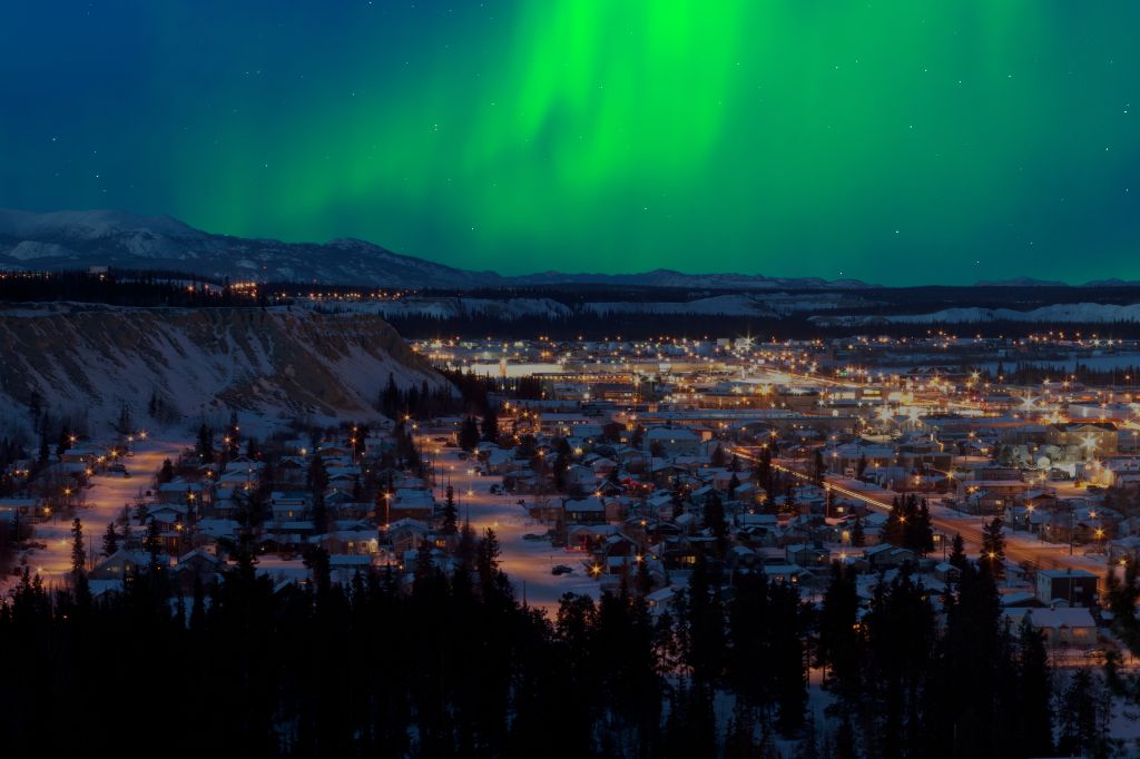 Strong northern lights (Aurora borealis) substorm on night sky over downtown Whitehorse, capital of the Yukon Territory, Canada, in winter.