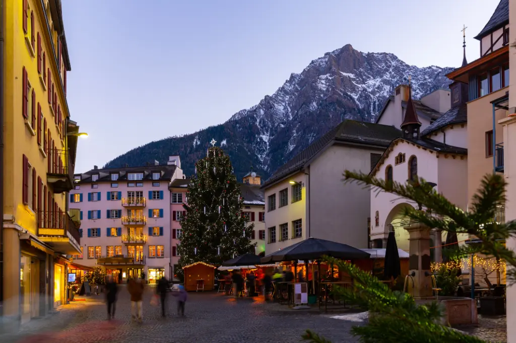 Evening view of Brig-Glis street with Christmas tree on background of Alpine peaks