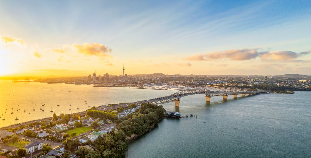 A panoramic image from above of Auckland, with the Sky Tower and CBD visible across Waitemata Harbor and the Auckland Harbour Bridge.