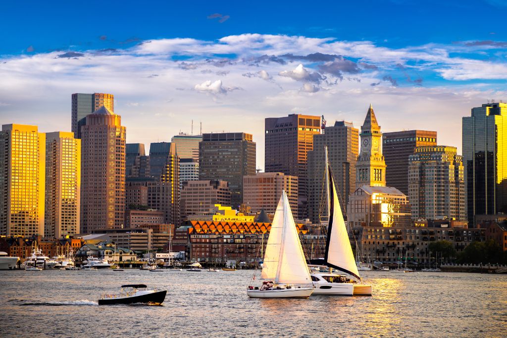 Boston downtown skyline panorama with skyscrapers over water with reflections at dusk illuminated with lights.